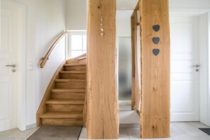 Un escalier en bois avec une rampe, des murs blancs et une porte dotée d’un trou de serrure.