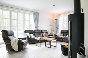 A modern living room with leather sofas, a coffee table, and a black fireplace.