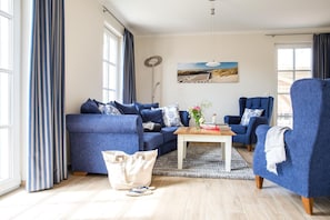 A living room with a blue sofa set, a coffee table, and a painting on the wall.