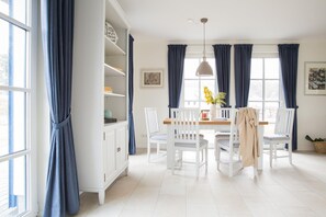 Un espace repas avec une table blanche, des chaises et un luminaire suspendu.
