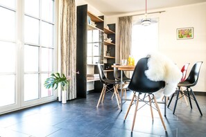 A modern dining area with a large window, a dining table with chairs, and a bookshelf.