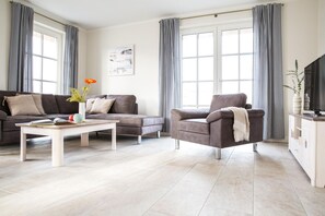 Una sala moderna con sofá, sillón y mesa de centro.