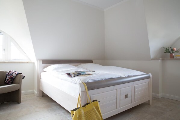 A bedroom with a bed, a chair, and a window.