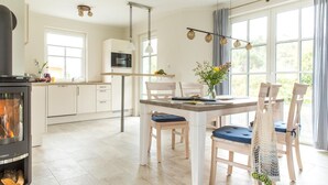 Een moderne keuken met witte kasten, een ingebouwde magnetron en een groot raam.