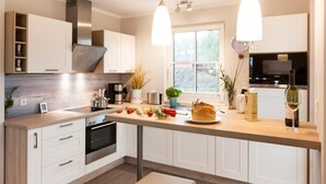 Cocina moderna con armarios blancos, encimera de madera e iluminación colgante.