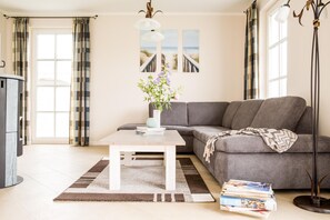 A modern living room with a grey sofa, a wooden coffee table, and a bookshelf.