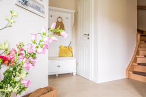 A clean, modern entryway with a white bench, a yellow handbag, and a welcome sign.