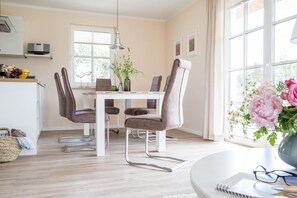 A dining area with a white table, four chairs, and a vase of flowers.