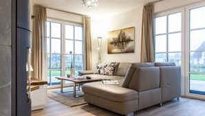 Una sala de estar moderna con un sofá modular, una mesa de centro y ventanas amplias que ofrecen vistas al exterior.