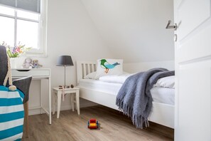 A child's bedroom with a bed, a desk, and a window.