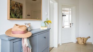 A hallway with a grey cabinet, a mirror, a hat, and a basket.