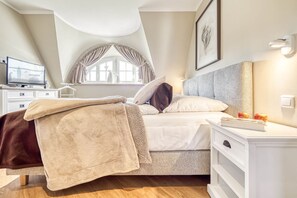 A bedroom with a bed, bedside table, and a window with curtains.