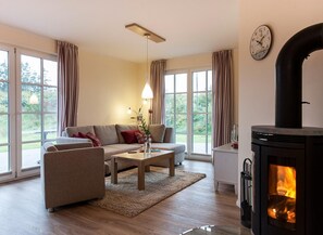 A living room with a sofa, coffee table, and a fireplace. - Haubenlerche 52 Vacation Home - Haubenlerche 52 Vacation Home - Close to Nature (Fuhlendorf)