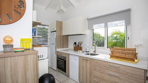 A modern kitchen with wooden cabinets, a built-in dishwasher, a sink, and a window with a view of greenery.