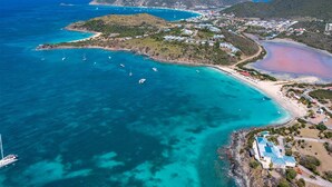 An aerial view of a coastal area with clear turquoise waters, a beach, and a small resort with a pool. - Blue Sailing | Ocean View - Located in  Wonderful Happy Bay with Private Pool (Saint Martin)