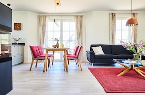 Ein modernes Wohnzimmer mit Essbereich, einer schwarzen Couch und einem roten Teppich.
