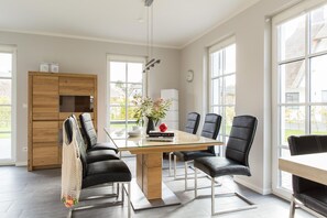Uma área de jantar moderna com mesa de madeira, cadeiras de couro preto e um vaso de flores.