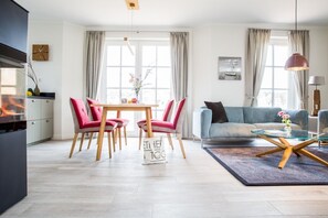 En moderne stue med en sofa, et sofabord i glas og et spiseområde med stole og bord.