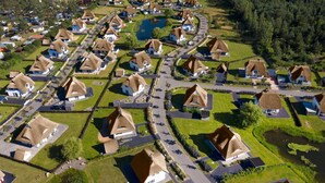 Un quartier résidentiel où les maisons sont dotées de toits de chaume et disposées selon un plan en forme de grille, avec un bassin d’eau central.