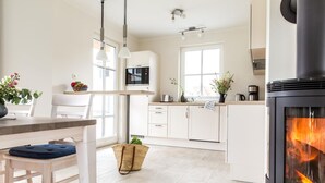 Une cuisine moderne avec des meubles blancs, un îlot central, une cuisinière intégrée et des luminaires suspendus.