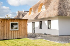Una casa moderna con techo de paja y estructura de madera a la izquierda.