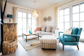 Una sala de estar moderna con sofá, sillón, mesa de centro y elementos decorativos.