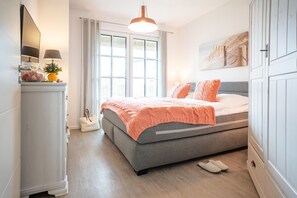 Ein Schlafzimmer mit einem Bett, einem Kleiderschrank, einem Spiegel, einem Fenster und einer Lampe.