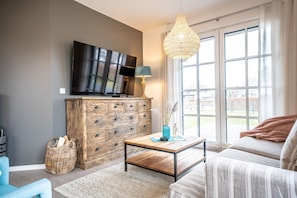 Un salón moderno con televisor, mueble de madera y un ventanal con vistas.