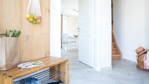A hallway with a wooden bench, a white door, and a staircase.