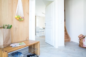 A hallway with a wooden bench, a white door, and a staircase.