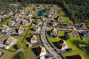 A residential area with houses featuring thatched roofs, arranged in a grid pattern with a central water body.