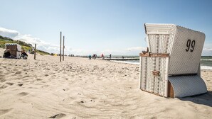 A beach with a wicker chair marked '99' and a wooden structure in the sand. - Vacation home Seeschwalbe 33 - Holiday home Seeschwalbe 33 - Close to nature (Fuhlendorf)