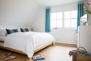 A bedroom with a bed, a window with curtains, a bedside table, and a small cabinet. - Vacation home Seeschwalbe 33 - Holiday home Seeschwalbe 33 - Close to nature (Fuhlendorf)