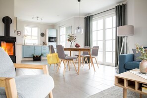 A modern living room with a fireplace, dining area, and a sofa. - Vacation home Seeschwalbe 33 - Holiday home Seeschwalbe 33 - Close to nature (Fuhlendorf)