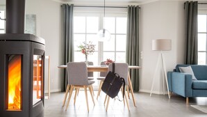 Un salon moderne avec un poêle à bois, un coin repas avec des chaises et une table, et un canapé bleu.