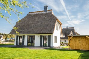 A modern house with a thatched roof, large windows, and a well-maintained lawn. - Vacation home Seeschwalbe 33 - Holiday home Seeschwalbe 33 - Close to nature (Fuhlendorf)