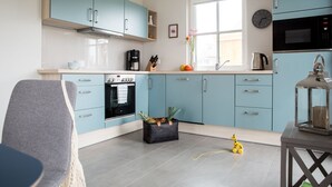 Une cuisine moderne avec des meubles de couleur bleu clair, un four encastré, un four à micro-ondes et une machine à café.