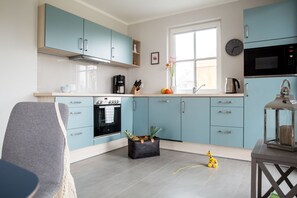 Een moderne keuken met lichtblauwe kastjes, een ingebouwde oven, een magnetron en een koffiezetapparaat.