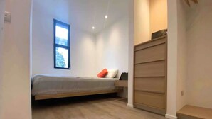 A bedroom with a bed, a window, and a built-in wardrobe. - Peaceful Home (Desamparados)