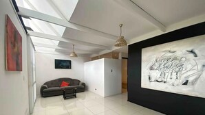 A modern living room with a grey sofa, a small table, and a large abstract painting on the wall. - Peaceful Home (Desamparados)