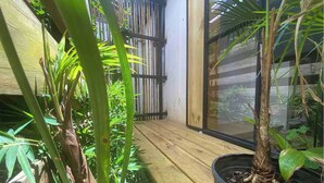A small, enclosed garden area with wooden flooring, potted plants, and a bamboo fence. - Peaceful Home (Desamparados)