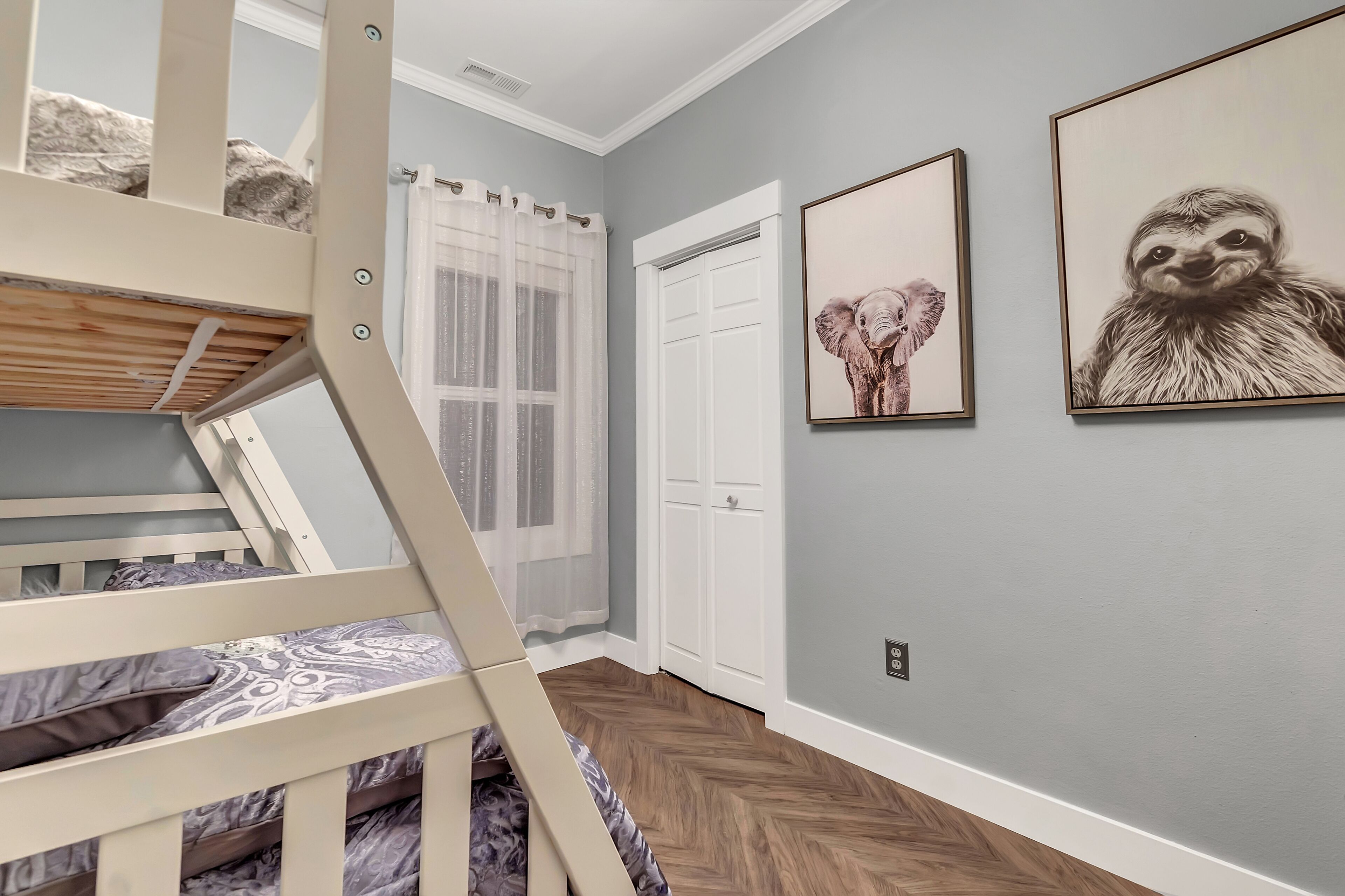 A room with a bunk bed, a door, and two framed pictures on the wall.