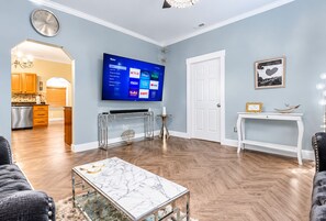 A living room with a flat-screen TV mounted on the wall, a marble coffee table, and a sofa. - 💎Urban Glam Gem💎 Rancher near Gonzaga w/GiG Internet (Spokane)