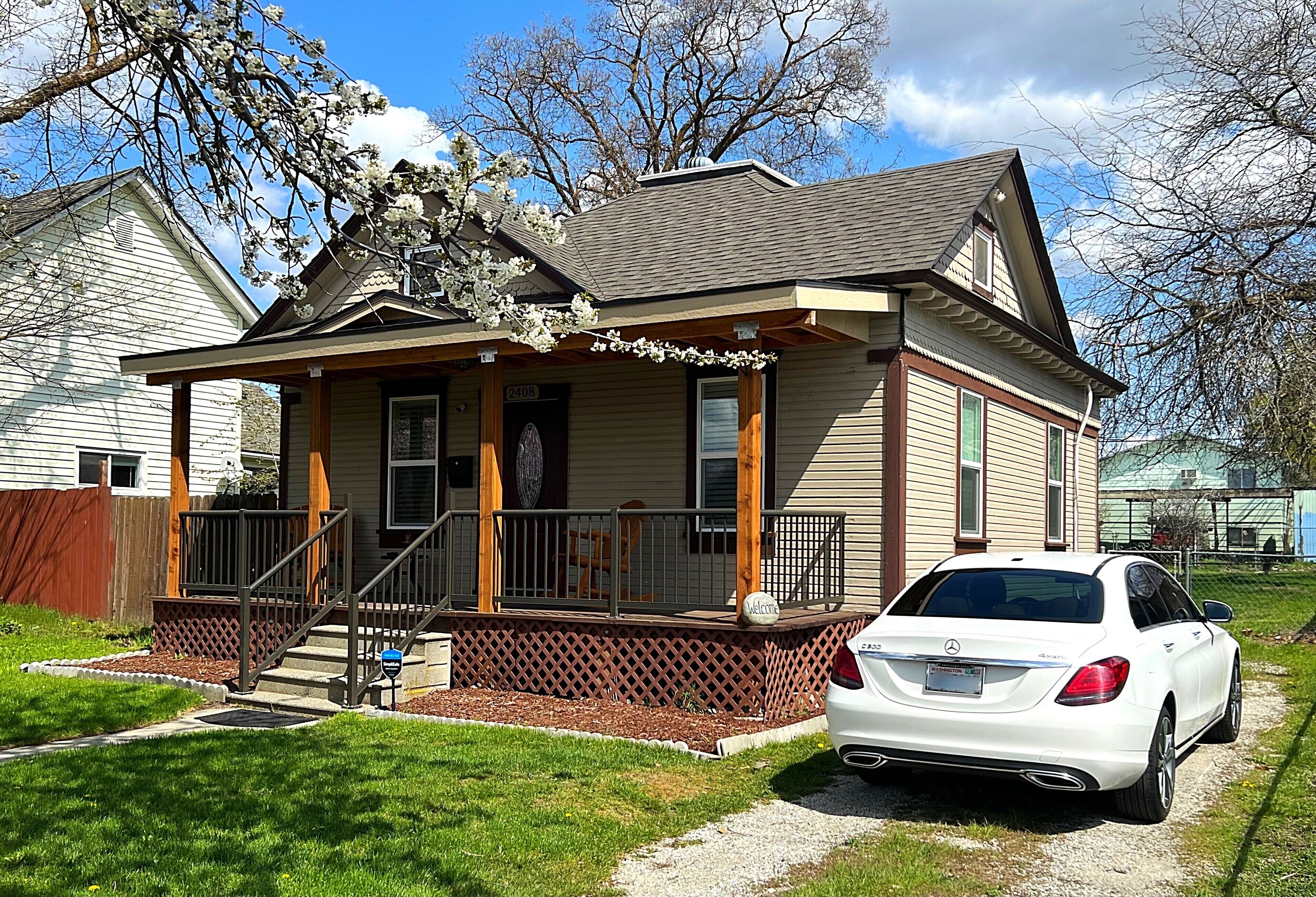 A two-story house with a front porch, a mailbox, and a parked white car.