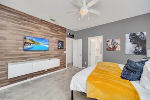 Relax in a spacious bedroom with a large bed, flat-screen TV, and ceiling fan.