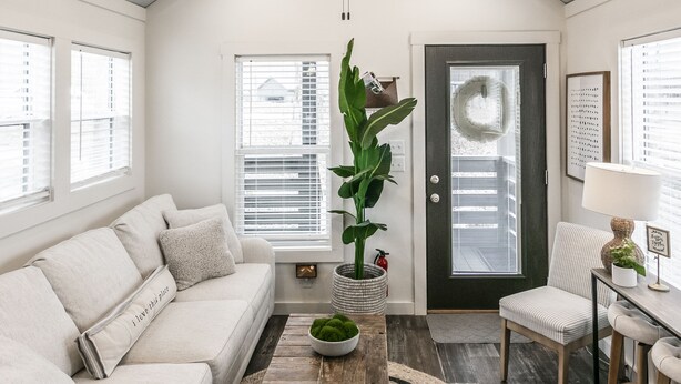 A modern living room with a ceiling fan, a sofa, a coffee table, and a door with a wreath. - Heavensent Tiny Home @ The Retreat at Water's Edge - Lake Views! (Tracy City)