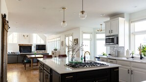 Een moderne keuken met een centraal eiland, witte kasten en een zithoek met een bank en stoelen.