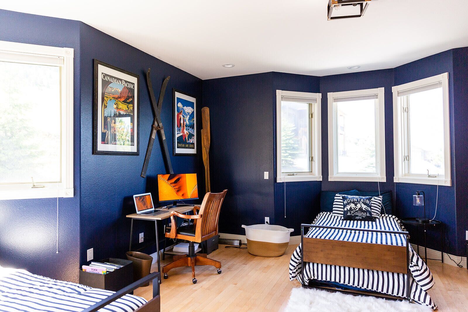 A bedroom with a bed, a desk with a computer, a chair, and a window.