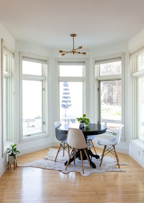 A dining area with a round table, four chairs, a chandelier, and large windows with a view of trees. - 🏔Views for Days! Welcome to the Missoula Lookout! 🏔 (Missoula)