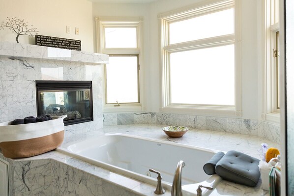 A modern bathroom with a large bathtub, a fireplace, and a window with a view. - 🏔Views for Days! Welcome to the Missoula Lookout! 🏔 (Missoula)